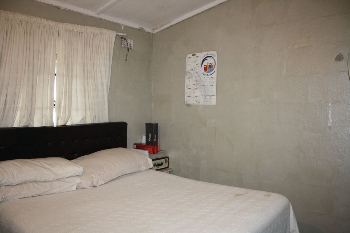 A bedroom featuring unfinished block walls and exposed electrical wiring, requiring cosmetic updates and repairs to improve the overall finish.