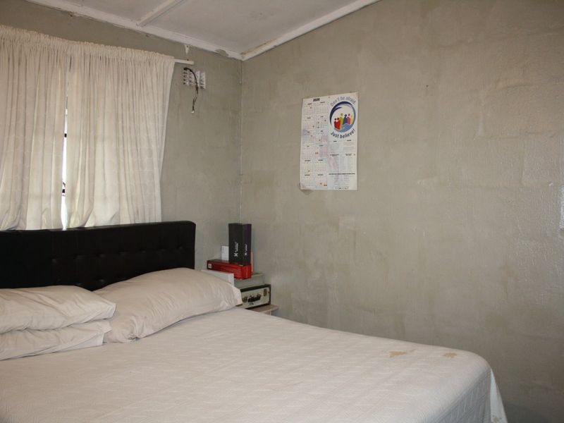 A bedroom featuring unfinished block walls and exposed electrical wiring, requiring cosmetic updates and repairs to improve the overall finish.