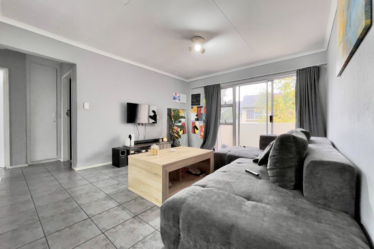 A living room featuring tiled flooring and a sliding glass door providing access to an outdoor area.