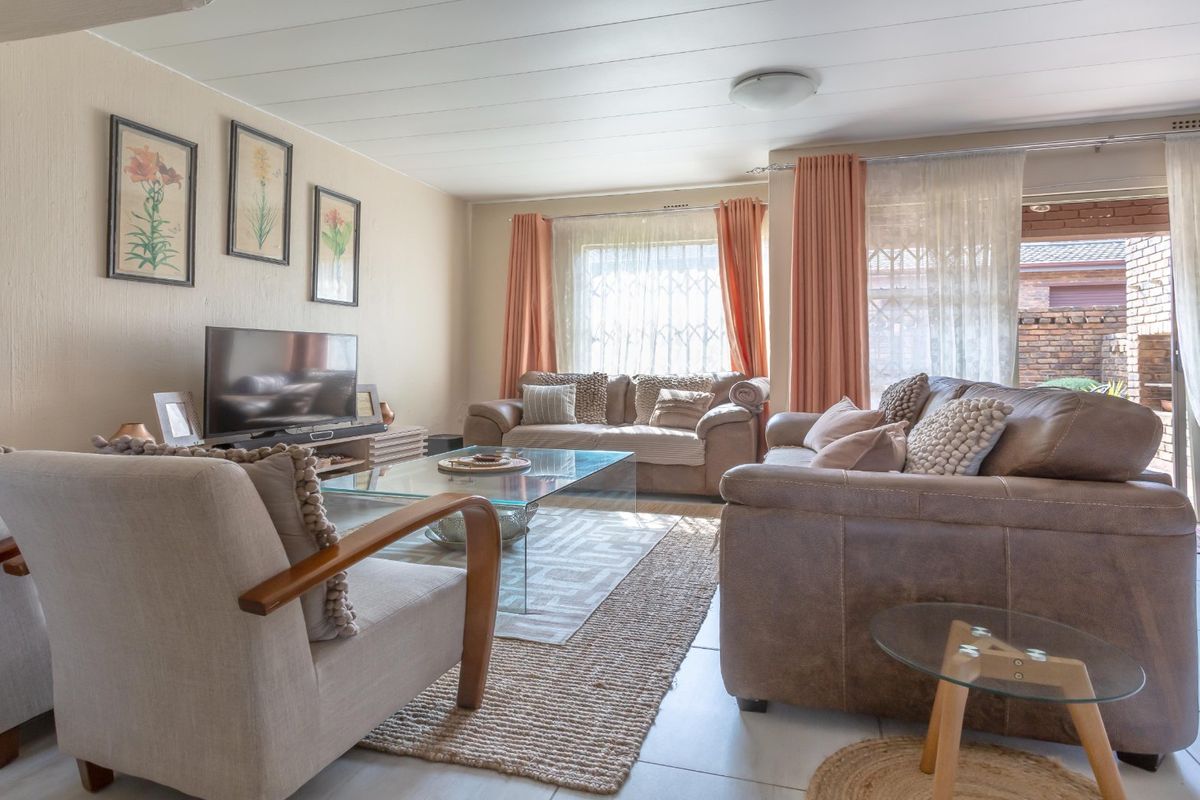 A comfortable living room featuring tiled flooring, large windows with natural light, and direct access to an outdoor patio area.