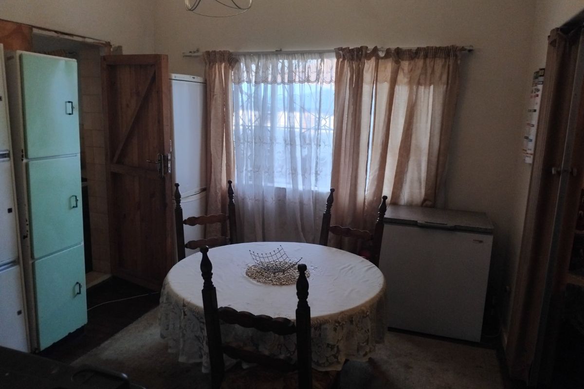 A dated kitchen area featuring a window with security bars and basic lighting, offering potential for modernization and layout improvement.