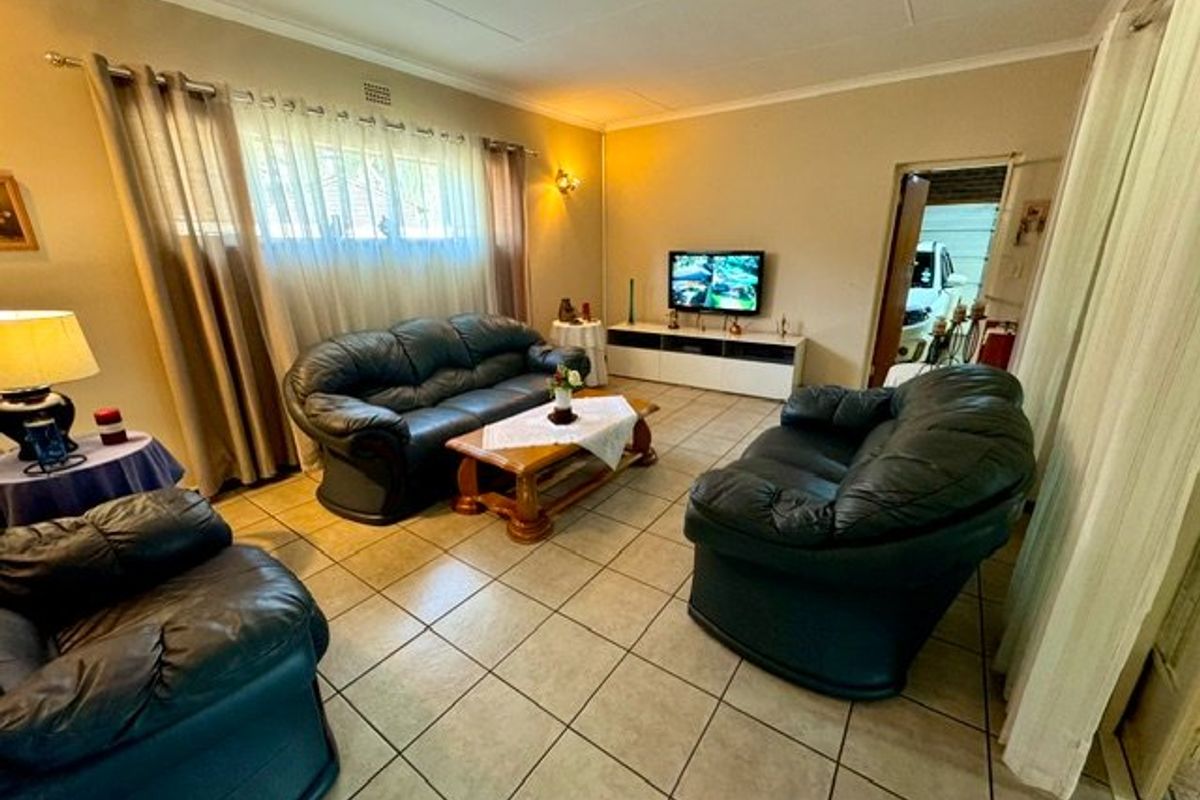 A spacious living room featuring neutral wall tones, tiled flooring, and large windows with curtain treatments, providing a comfortable and functional family area.