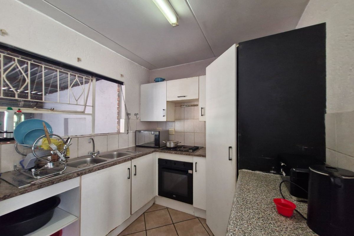 Compact kitchen featuring built-in cabinetry, a double sink, integrated oven and hob, and tiled flooring, offering a functional layout with potential for modernization.