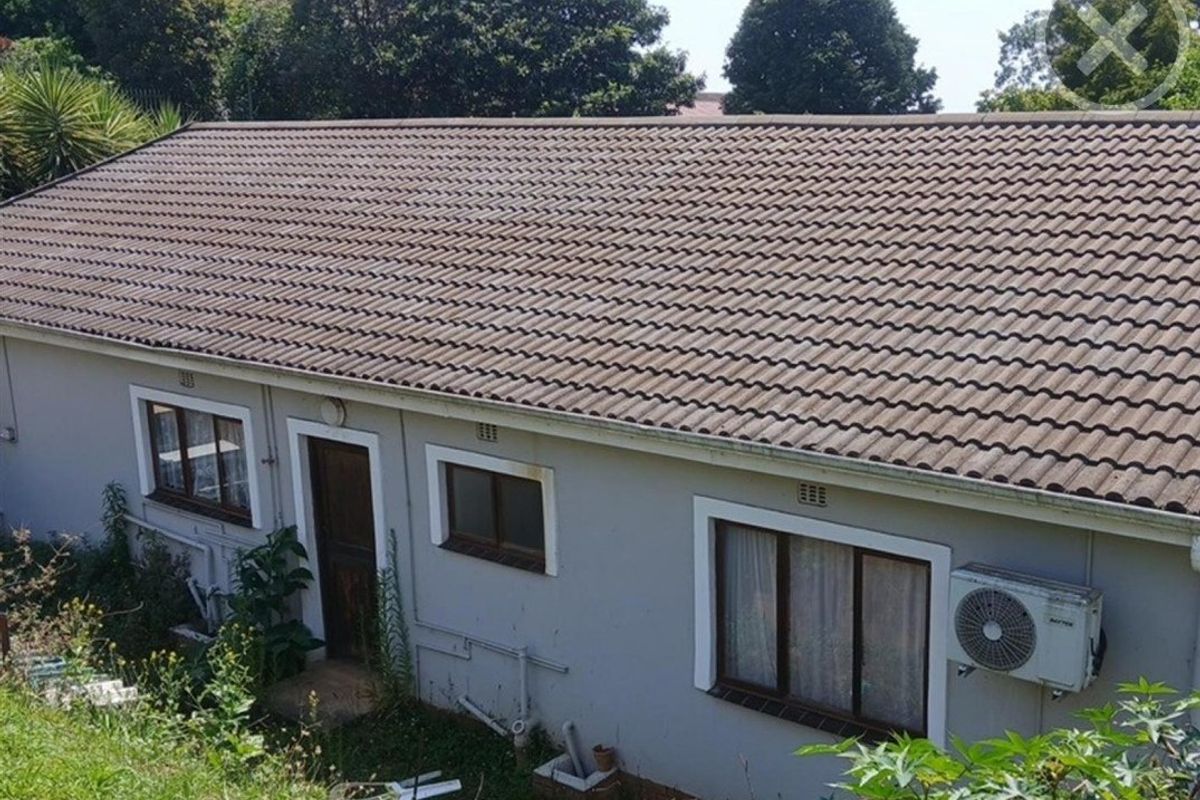 Rear exterior view of a single-story house featuring a tiled roof, air conditioning unit, and standard window and door frames.