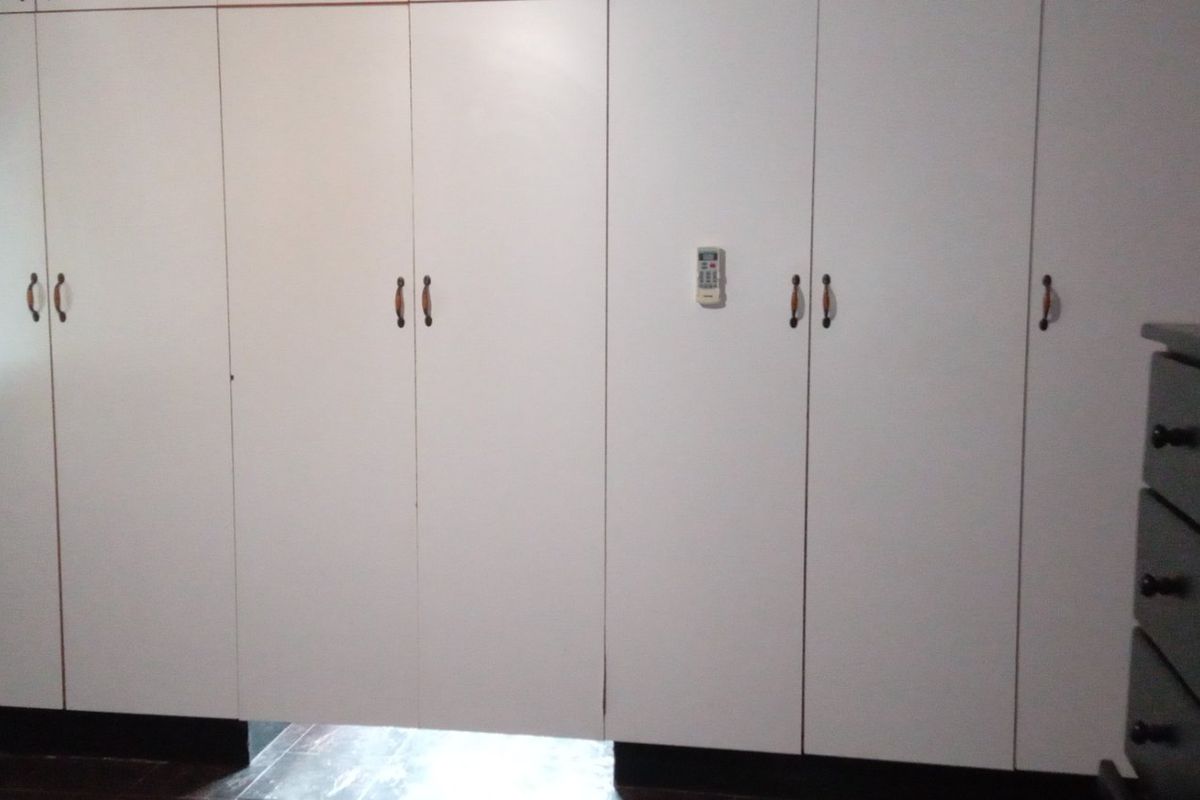 A bedroom featuring extensive white built-in cupboards providing ample storage space.