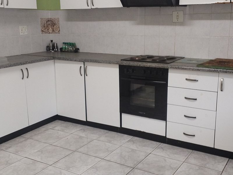 A functional kitchen featuring white cabinetry, laminate countertops, a built-in oven, and an electric hob with a tiled backsplash.