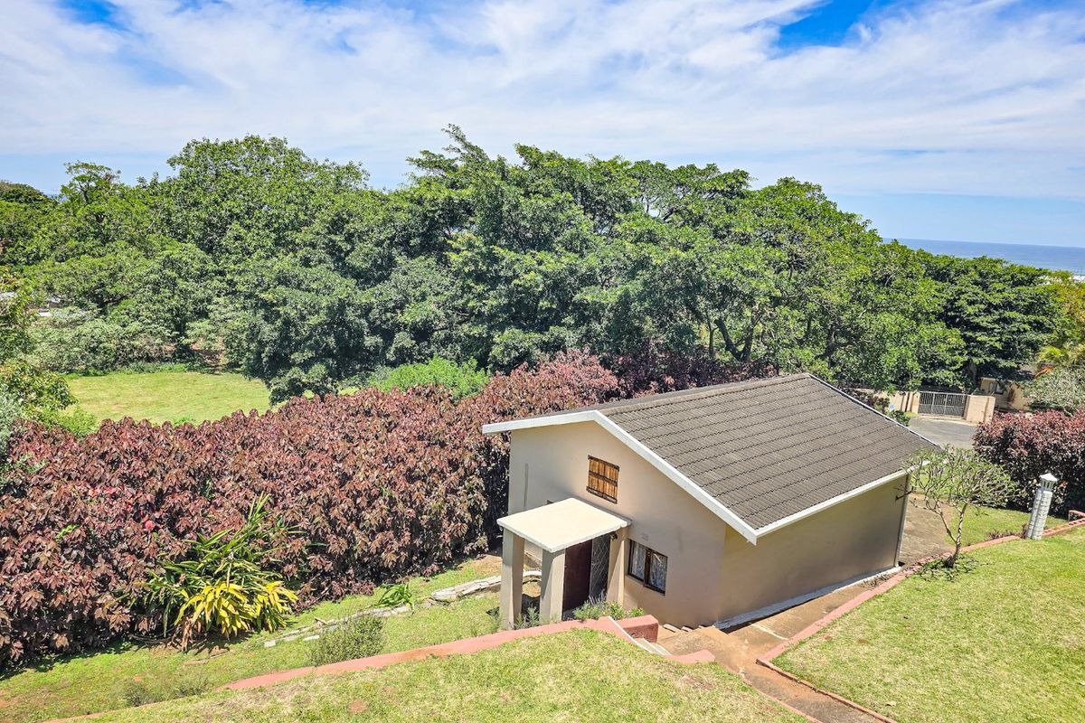 Aerial view of a detached residential property featuring a tiled roof, set within a landscaped garden with mature trees and paved pathways.