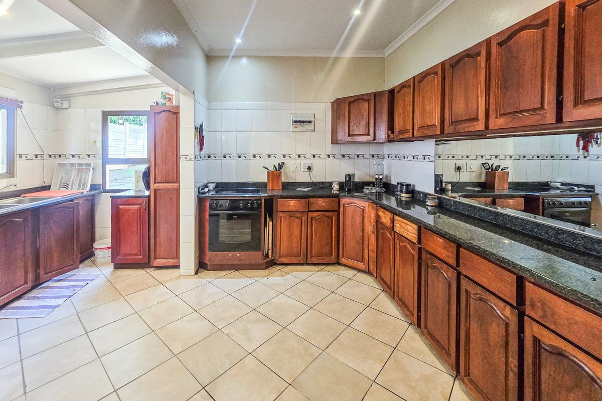 Spacious kitchen featuring traditional wooden cabinetry, granite countertops, tiled flooring, and a built-in oven, offering a functional layout with ample storage space.