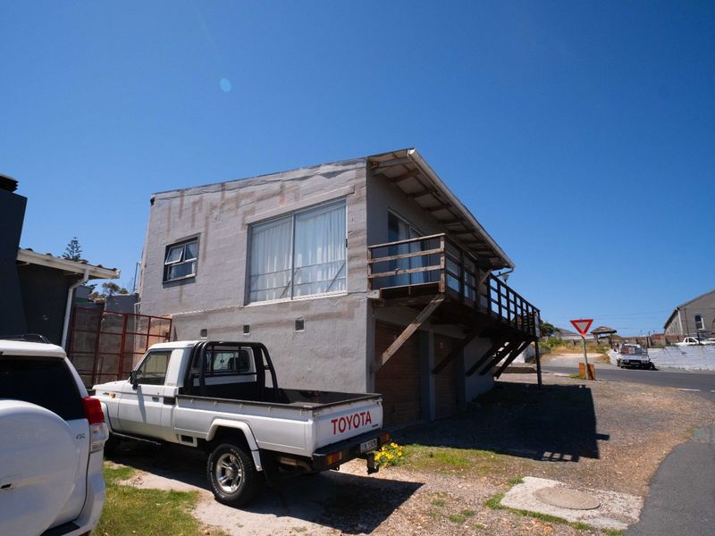 Exterior view of a two-story apartment building featuring a timber balcony, sliding glass doors, and ground-level garage access.