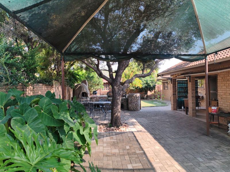 Spacious outdoor patio area featuring brick paving, a built-in pizza oven, and a shade cloth canopy, perfect for outdoor entertaining.