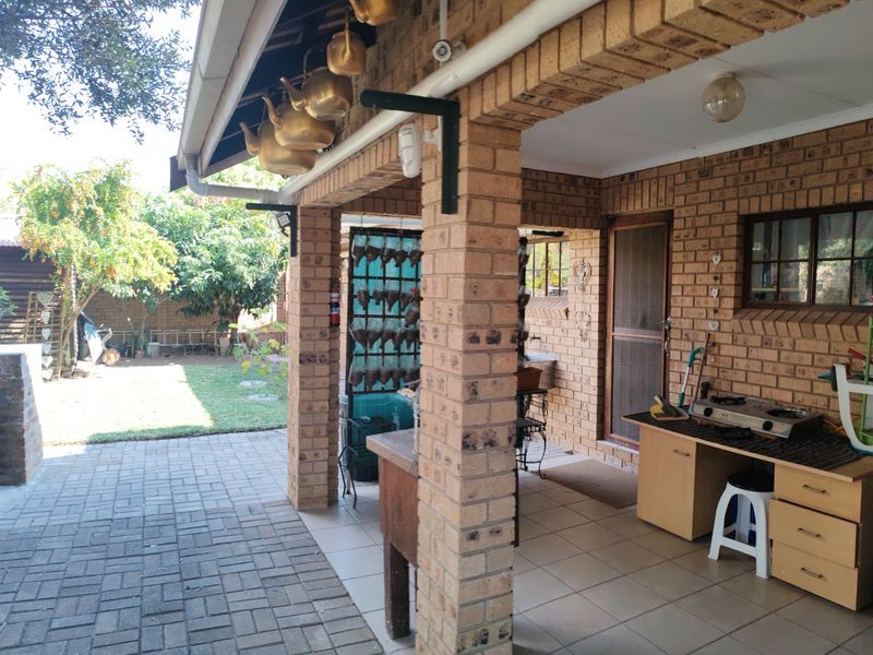 Covered outdoor patio featuring brick construction, tiled flooring, and a built-in brick braai, overlooking a private garden area.