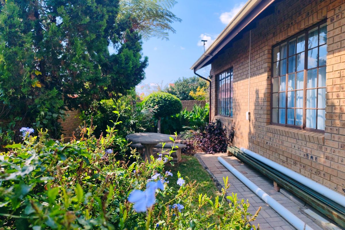 A view of the rear exterior featuring a brick facade, paved walkway, and established garden area.