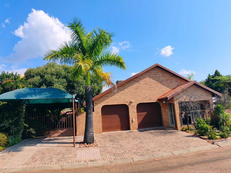 Front elevation of a brick house featuring a double garage, paved driveway, and an additional shade cloth carport.