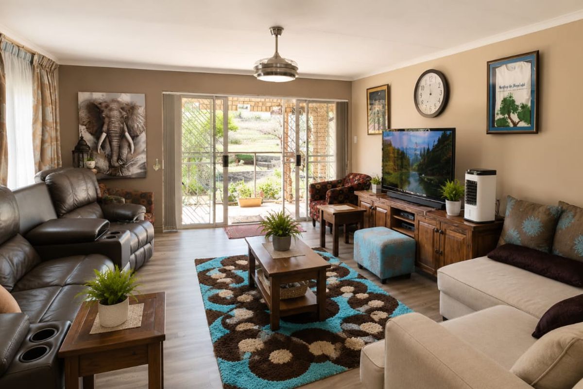 A comfortable living room featuring laminate flooring, a ceiling fan, and large sliding glass doors that provide natural light and access to the outdoors.
