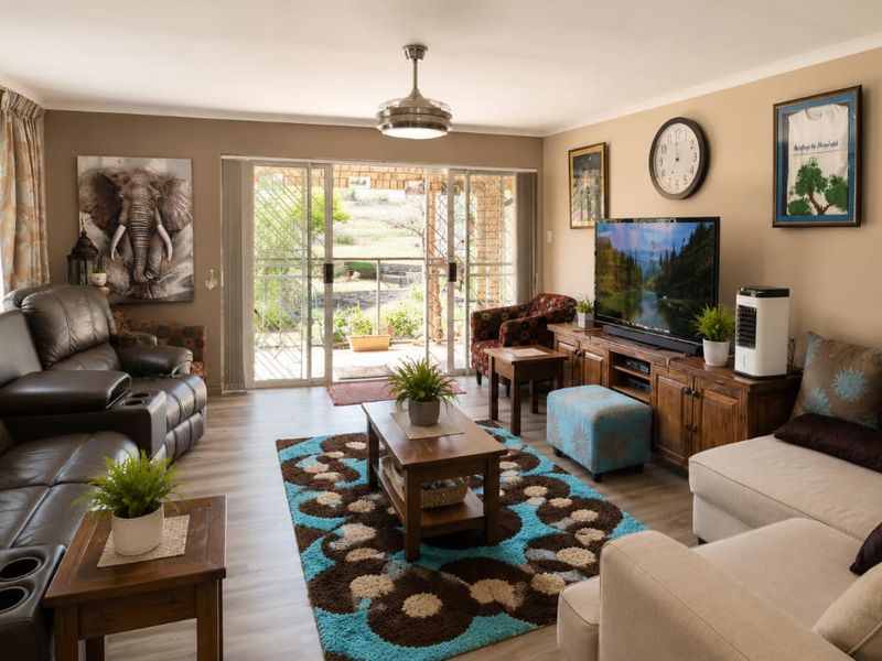 A comfortable living room featuring laminate flooring, a ceiling fan, and large sliding glass doors that provide natural light and access to the outdoors.