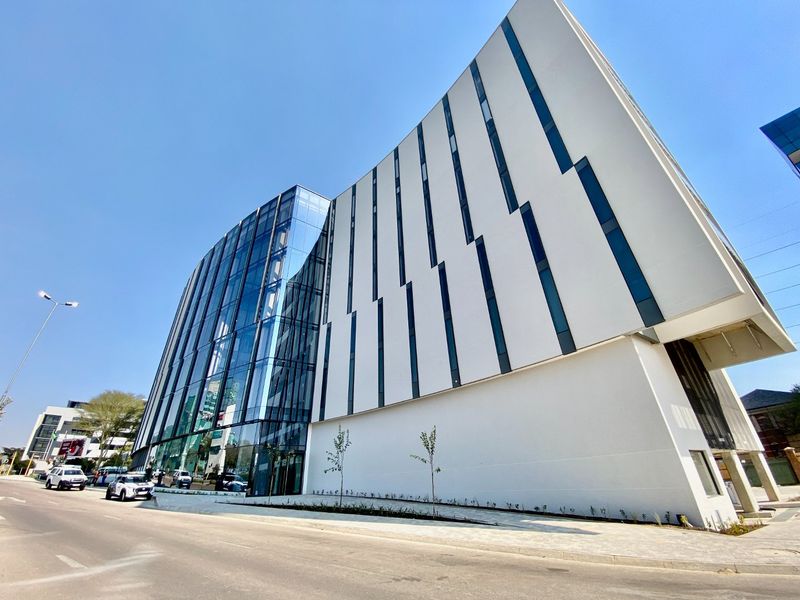 Modern commercial building featuring a striking glass curtain wall and contemporary white facade with vertical window detailing.