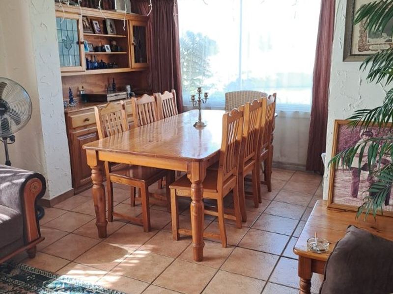A dining room featuring ceramic floor tiles, textured walls, and built-in wooden cabinetry, offering a functional space for family meals.