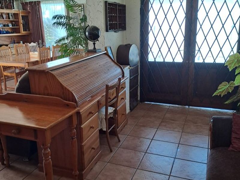 A living area featuring ceramic floor tiles, textured walls, decorative ceiling cornices, and double wooden doors with diamond-patterned glass inserts.