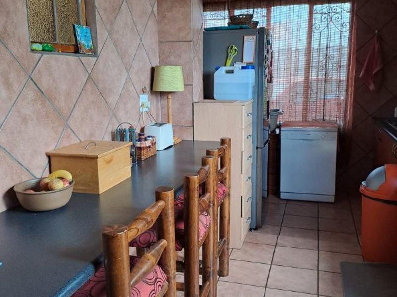 A functional kitchen area featuring tiled walls and flooring with a built-in breakfast bar counter.