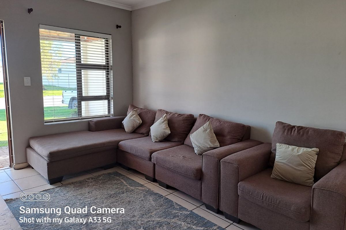 A living room featuring tiled flooring, a large window with horizontal blinds, and a sliding door providing access to the exterior.