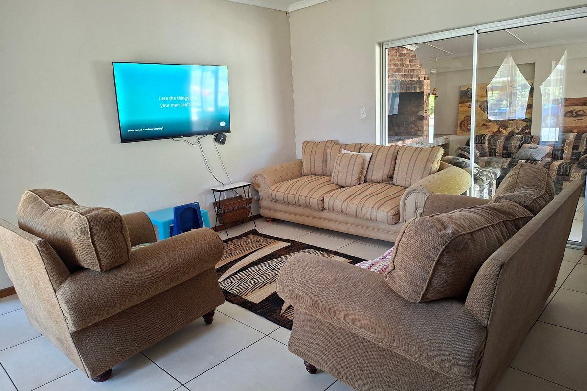 A spacious living room featuring neutral tiled flooring and large sliding glass doors that provide natural light and access to the outdoor area.