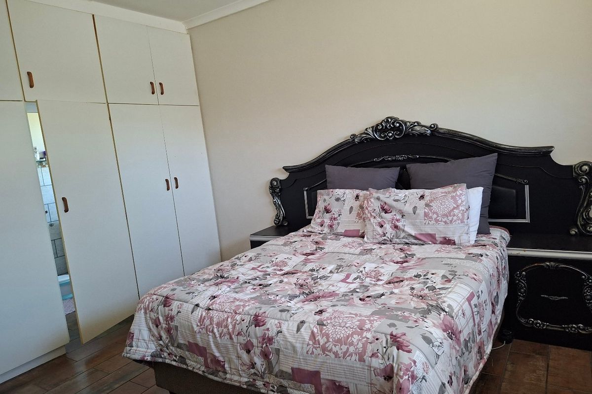 A bedroom featuring built-in cupboards and tiled flooring, providing a functional space with neutral wall finishes.