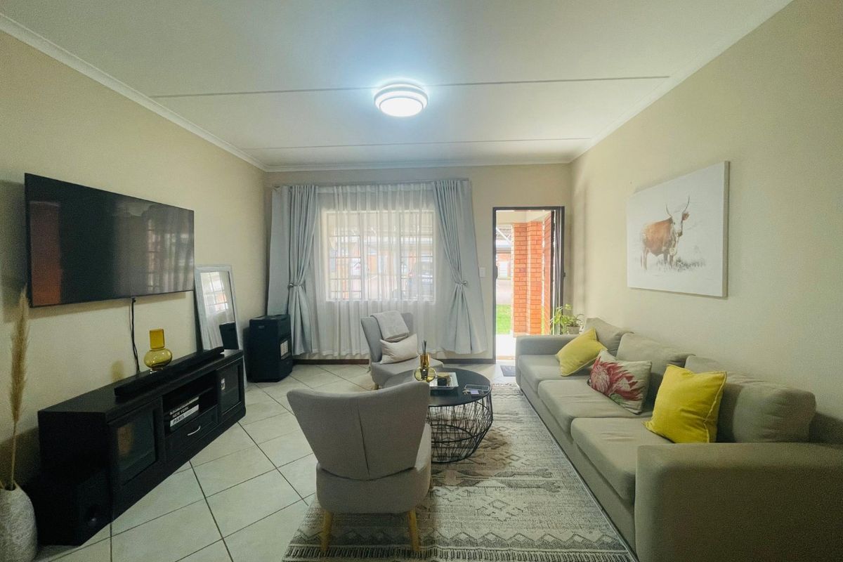 A well-lit living room featuring tiled flooring and direct access to an outdoor area, providing a comfortable and functional space.