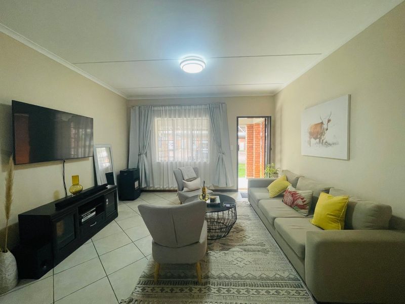 A well-lit living room featuring tiled flooring and direct access to an outdoor area, providing a comfortable and functional space.