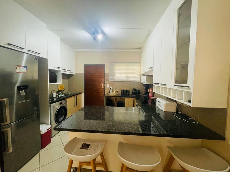 A functional kitchen featuring granite countertops, ample built-in cabinetry, a breakfast bar, and tiled flooring, with a convenient layout for daily meal preparation.