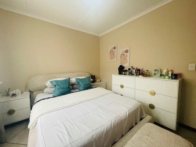 A well-maintained bedroom featuring neutral wall tones, tiled flooring, and coved ceiling detailing, providing a comfortable and functional living space.