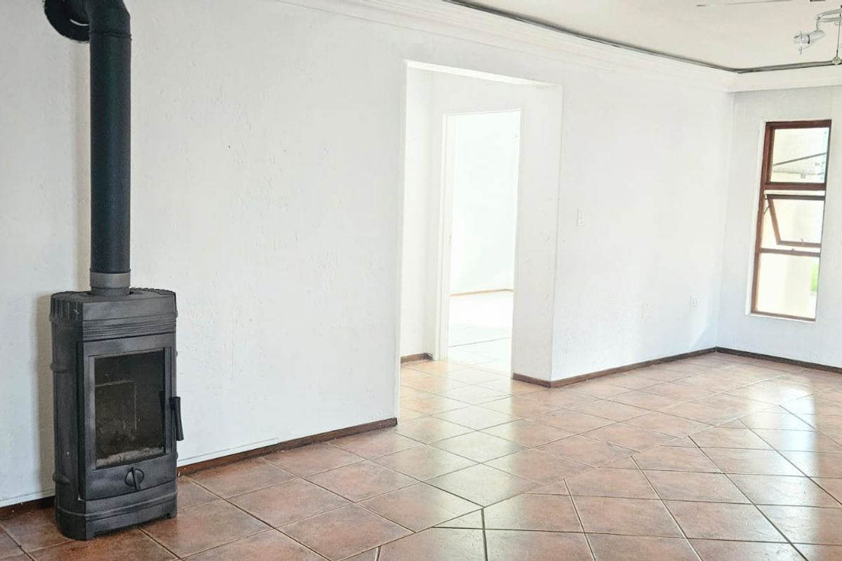 Spacious living area featuring ceramic tile flooring and a prominent freestanding fireplace, offering a blank canvas for interior design.