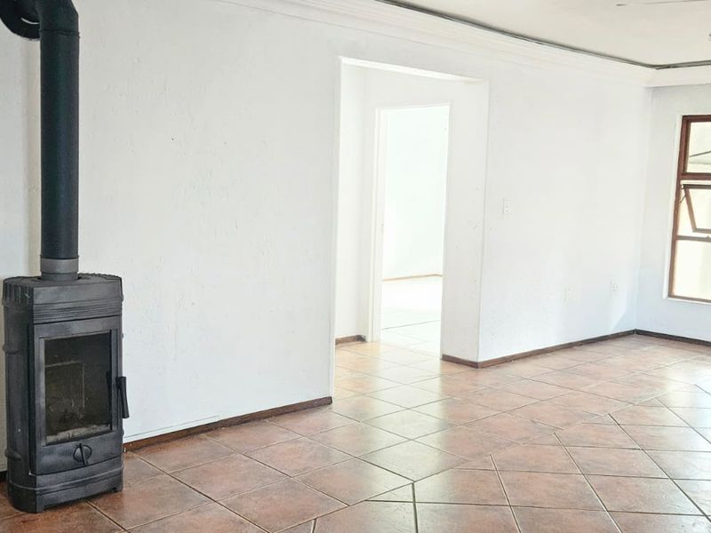 Spacious living area featuring ceramic tile flooring and a prominent freestanding fireplace, offering a blank canvas for interior design.