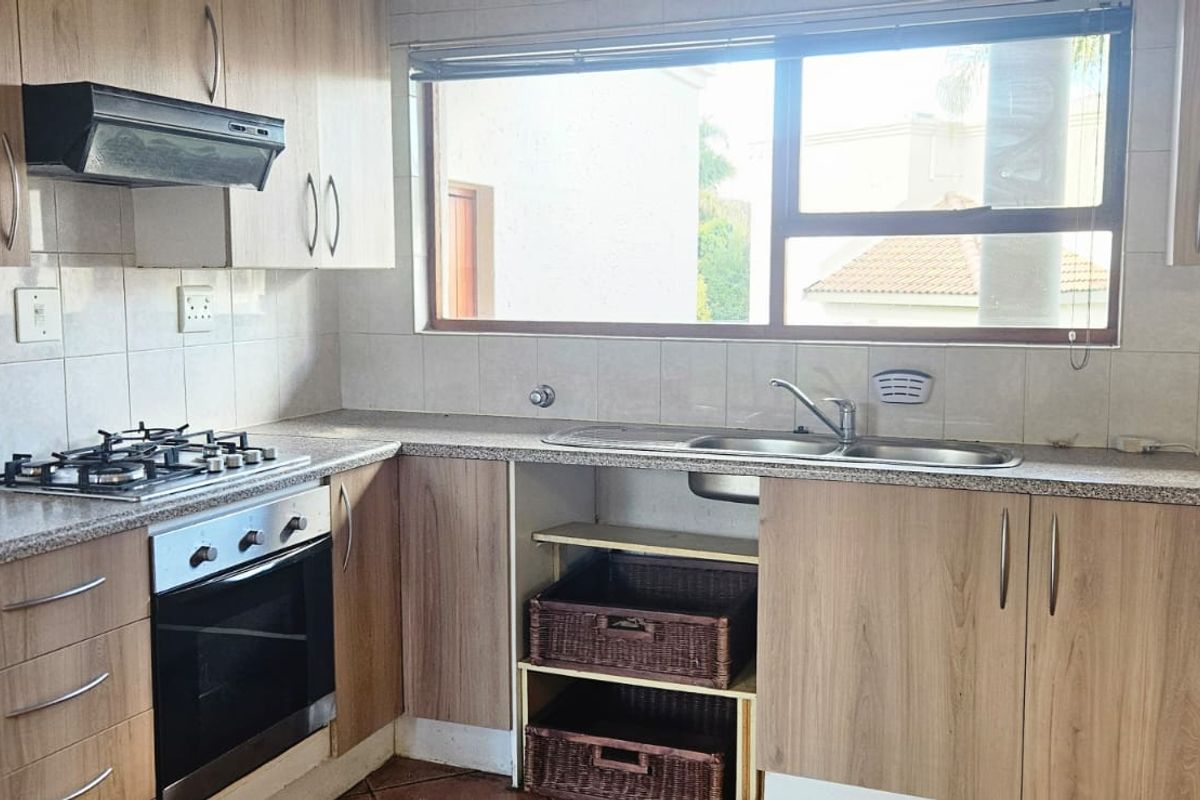 Functional kitchen featuring light wood cabinetry, gas hob, built-in oven, extractor fan, and a double bowl sink with tiled backsplash.