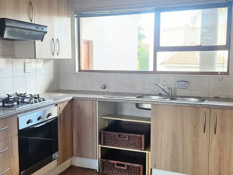 Functional kitchen featuring light wood cabinetry, gas hob, built-in oven, extractor fan, and a double bowl sink with tiled backsplash.