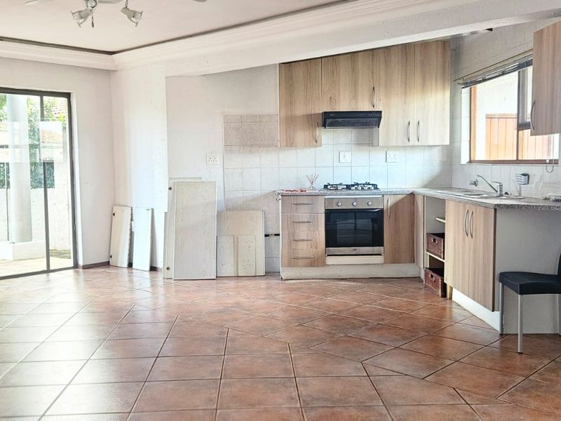 Open-plan living and kitchen area featuring tiled floors, built-in cabinetry, and direct access to the outdoor patio through sliding glass doors.