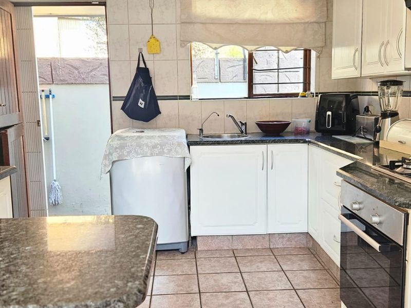 A functional kitchen featuring granite countertops, built-in cabinetry, a gas hob, and an integrated oven, with direct access to an outdoor area.
