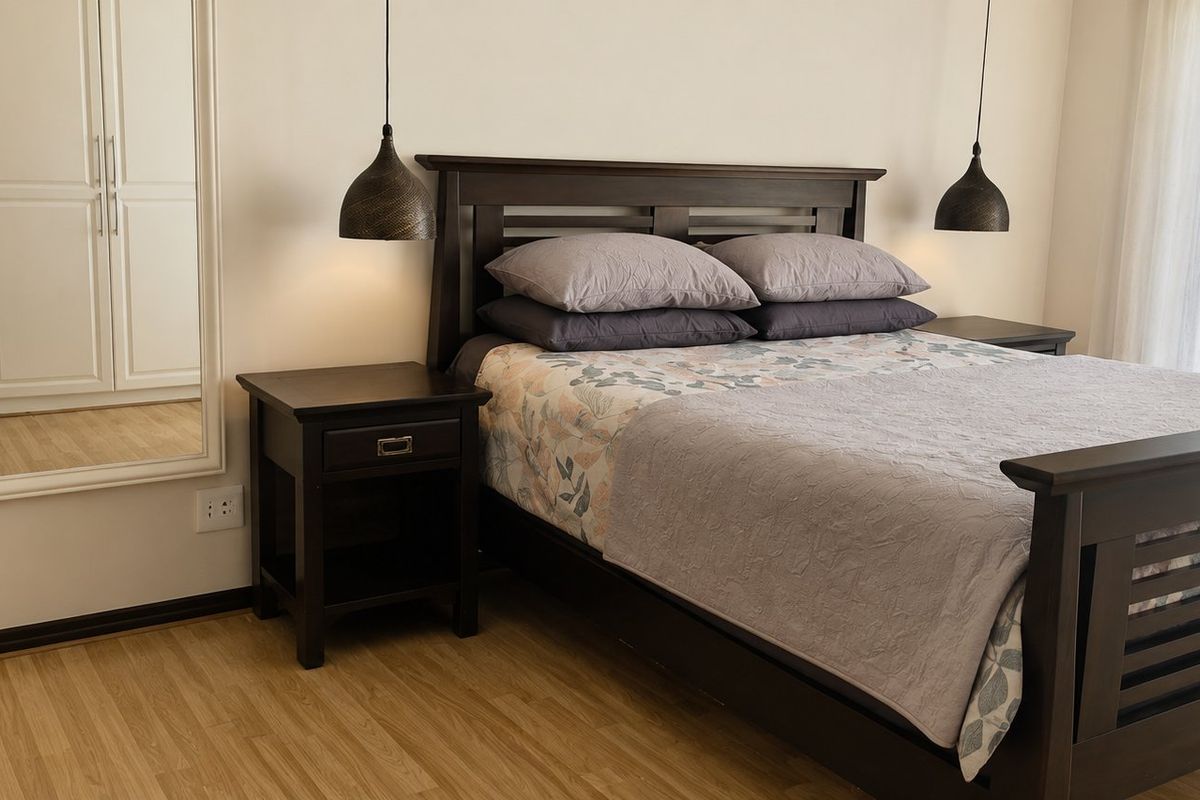 A well-maintained bedroom featuring laminate flooring, built-in wardrobe storage, and modern pendant lighting.