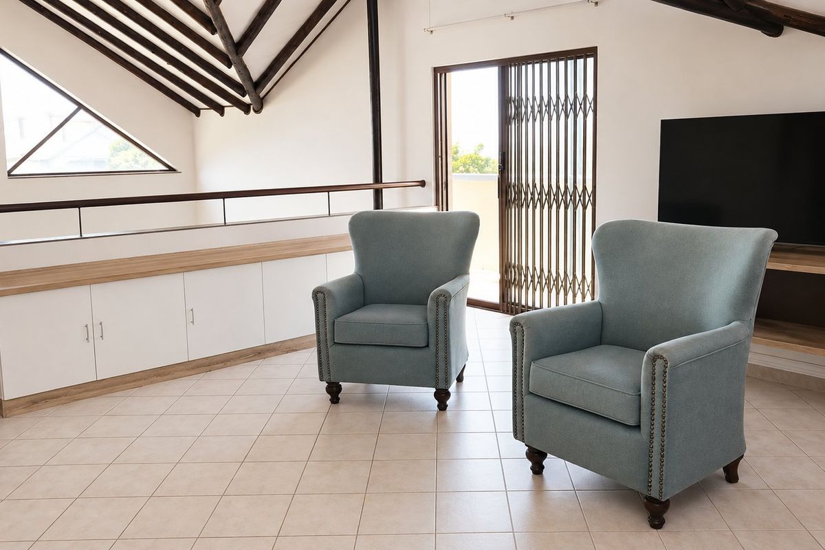 Spacious living area featuring a vaulted ceiling with exposed timber beams, built-in cabinetry, tiled flooring, and access to an outdoor area via sliding doors.