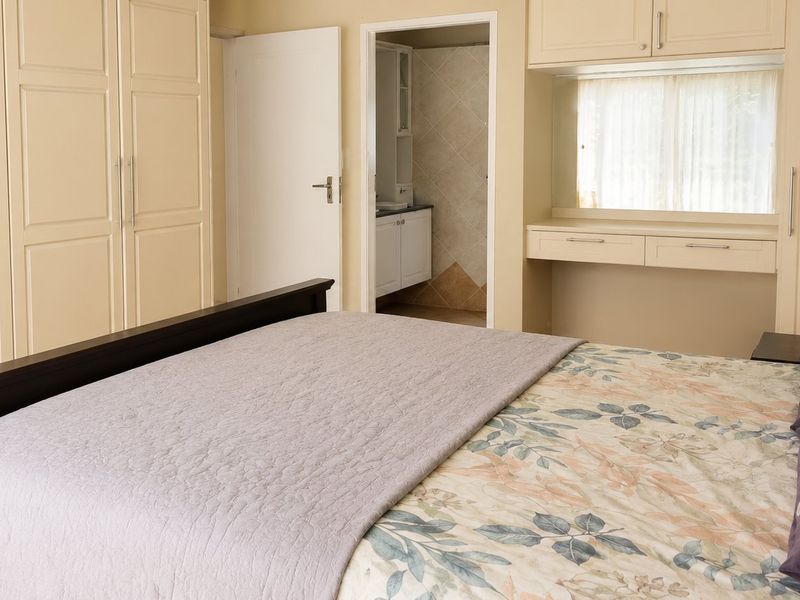 A well-maintained bedroom featuring extensive built-in cabinetry, a dedicated vanity area, and direct access to an en-suite bathroom.