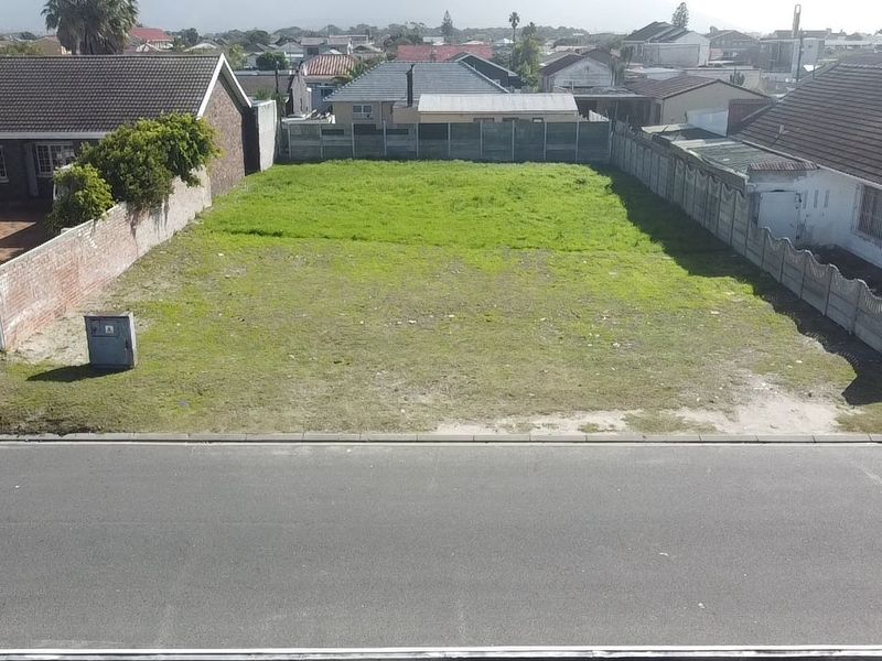 A vacant residential plot situated between existing homes, featuring established boundary walls and street-front access in a developed suburban neighbourhood.