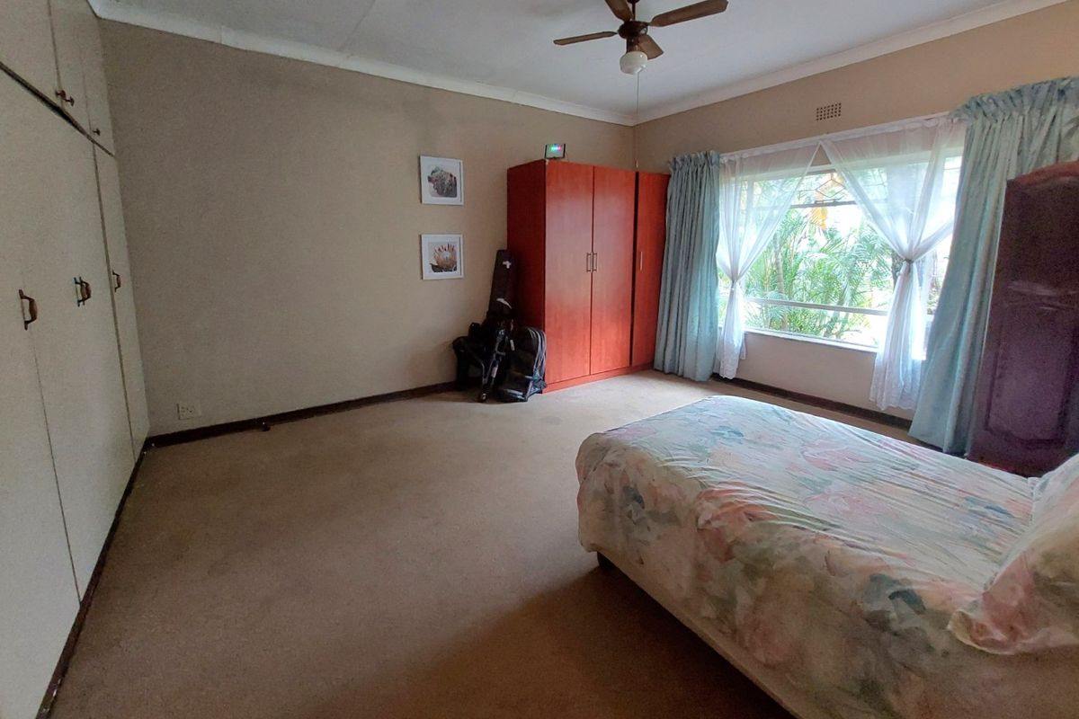 Spacious bedroom featuring built-in cupboards, a ceiling fan, and large windows allowing for natural light.