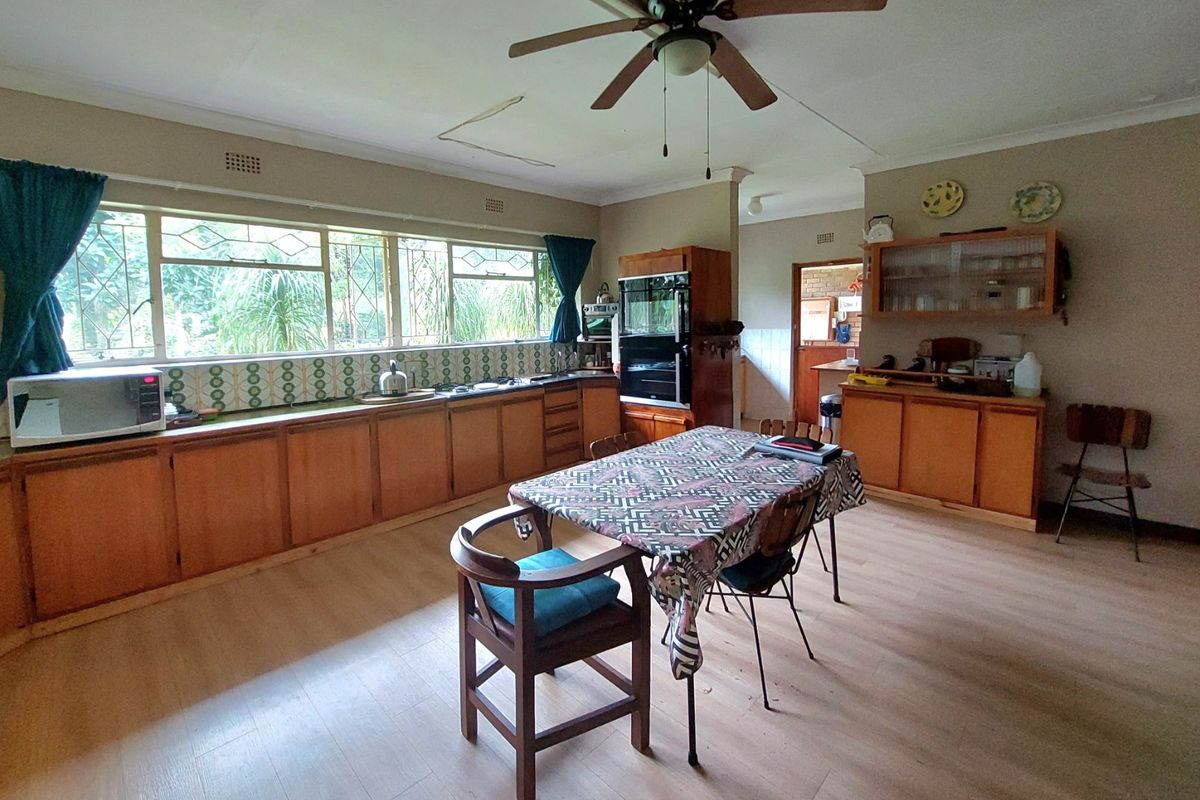 Spacious kitchen featuring extensive wooden cabinetry, a tiled backsplash, built-in oven, and large windows providing natural light, with potential for modern updates.