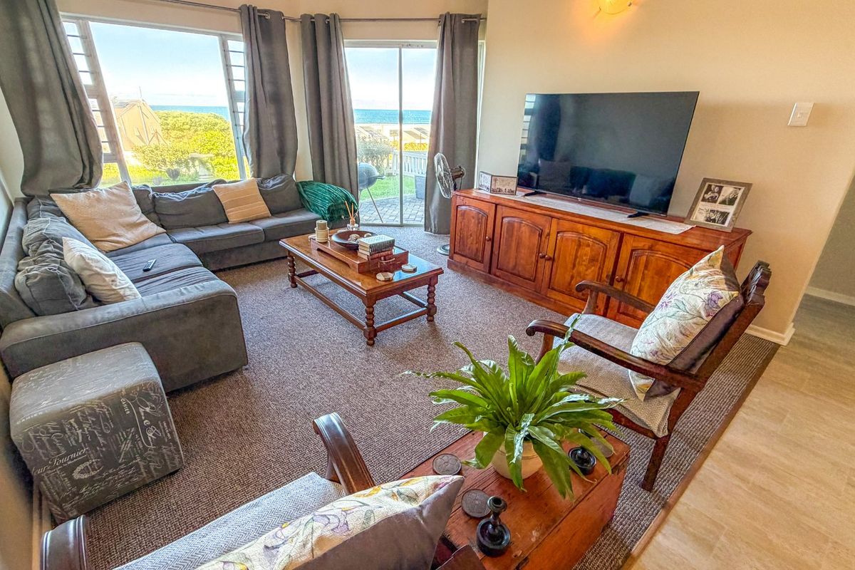 A comfortable living room featuring large windows and sliding glass doors that provide natural light and views of the outdoors.