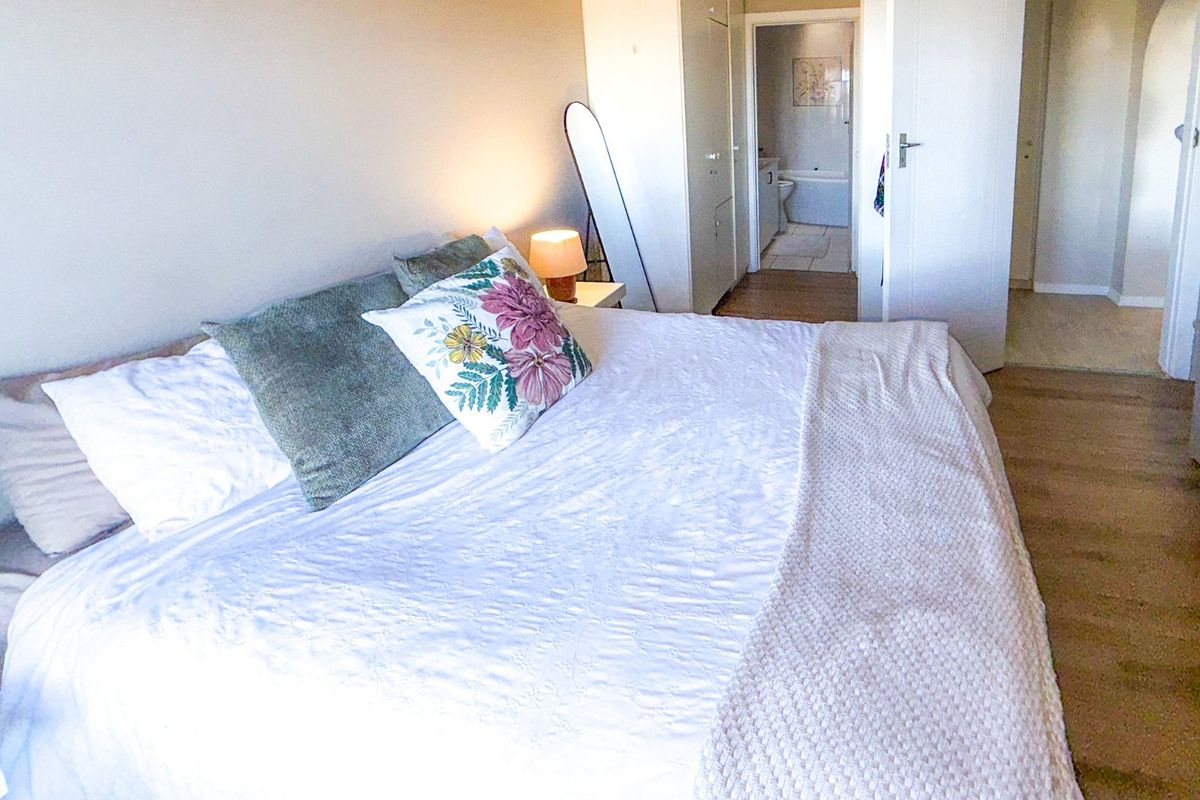 A well-lit bedroom featuring laminate flooring, built-in cupboards, and direct access to an en-suite bathroom.