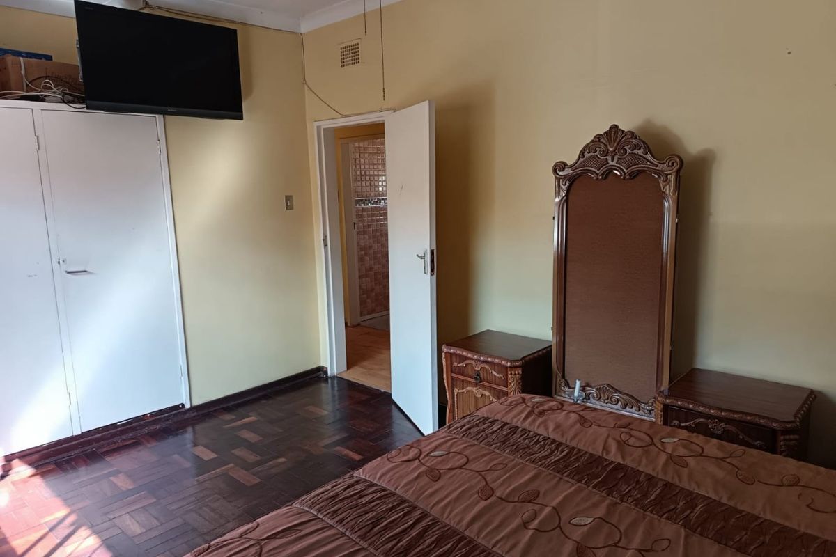 Bedroom featuring parquet flooring, built-in wardrobe, and direct access to an adjoining bathroom.