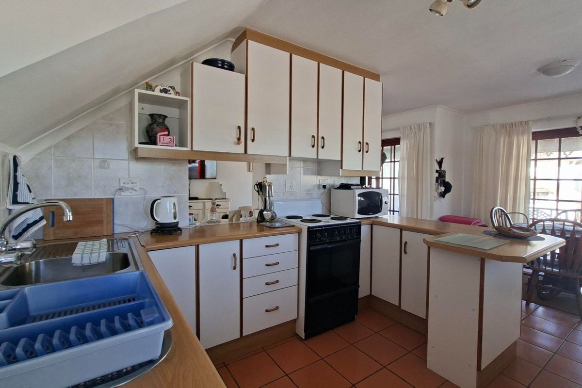 A functional kitchen featuring white cabinetry, laminate countertops, tiled flooring, and a built-in electric stove, offering a practical layout with potential for modern updates.