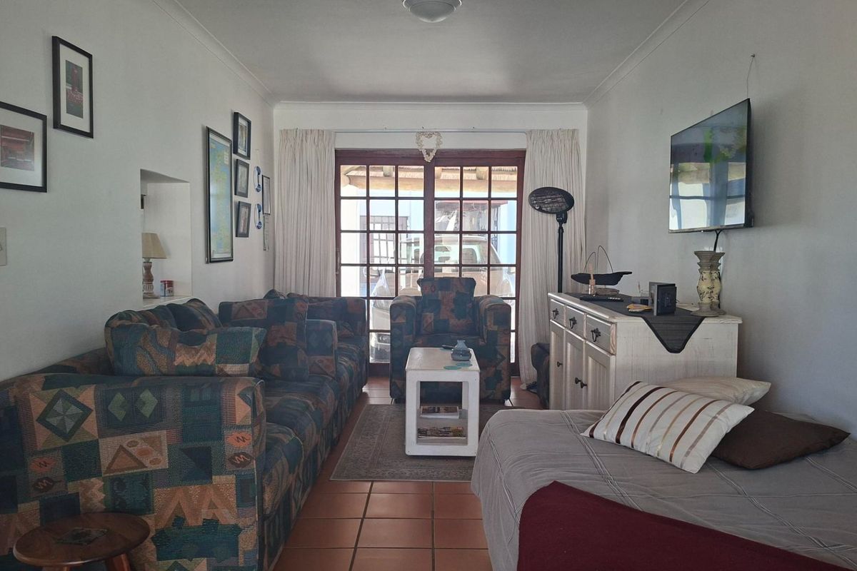 A comfortable living room featuring terracotta floor tiles and timber-framed glass doors providing access to the outdoor area.