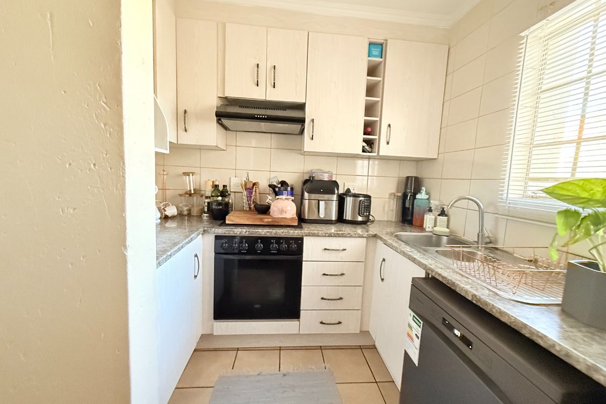 Compact kitchen featuring light-toned cabinetry, granite-look laminate countertops, built-in oven with extractor fan, and tiled flooring.