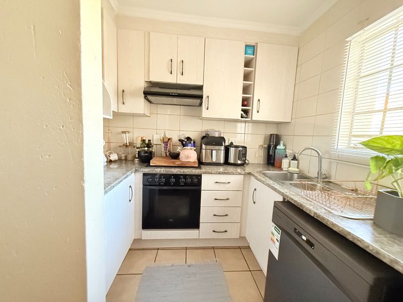 Compact kitchen featuring light-toned cabinetry, granite-look laminate countertops, built-in oven with extractor fan, and tiled flooring.