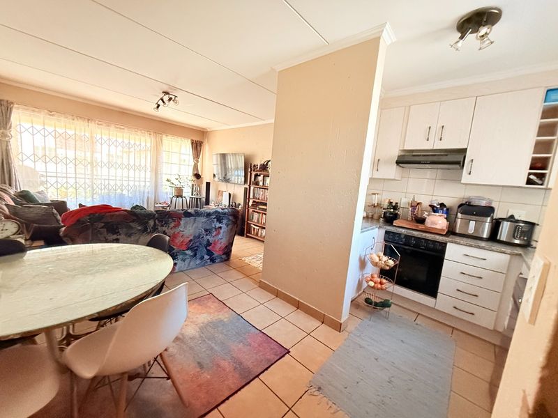Open-plan living and kitchen area featuring tiled flooring, built-in cabinetry, and an integrated oven with extractor fan.